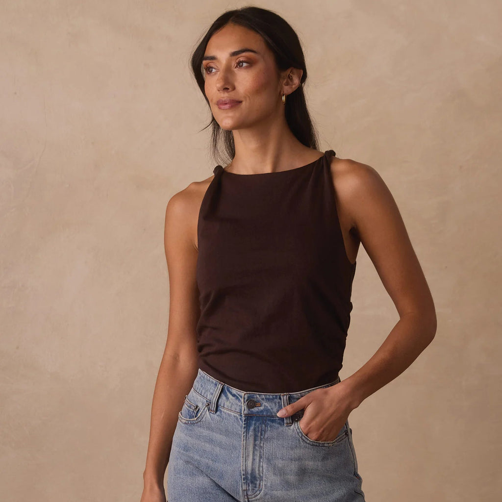 Woman wearing a brown tank top from The Normal Brand and denim shorts sold at District Trading Company in Salem, MA.